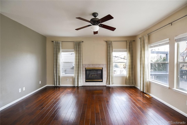 unfurnished living room with dark hardwood / wood-style flooring, ceiling fan, and a tiled fireplace