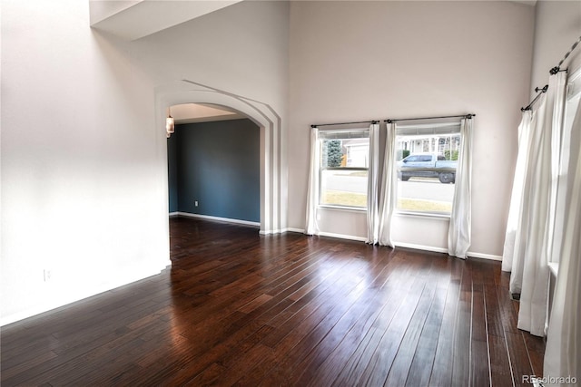 unfurnished room with a high ceiling and dark wood-type flooring