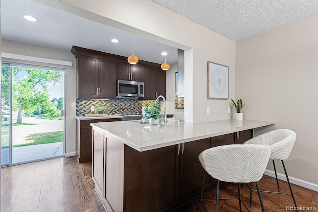4452 W Pondview Dr, Littleton, CO 80123 - kitchen with stainless steel microwave, dark brown cabinetry, wood finished floors, decorative backsplash, and recessed lighting