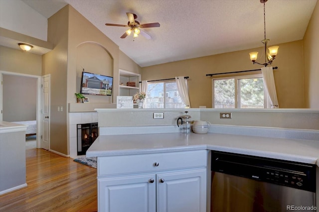 kitchen featuring lofted ceiling, a fireplace, light countertops, a textured ceiling, and dishwasher