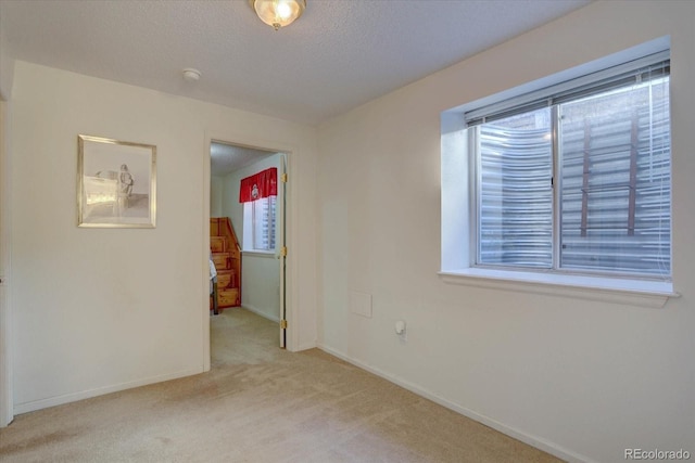 carpeted spare room featuring baseboards and a textured ceiling