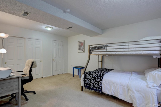 carpeted bedroom with baseboards, visible vents, and a textured ceiling