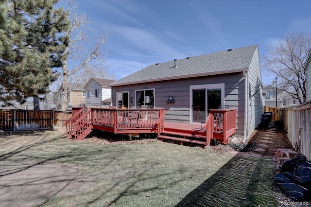 rear view of property with a deck, a fenced backyard, and a shingled roof