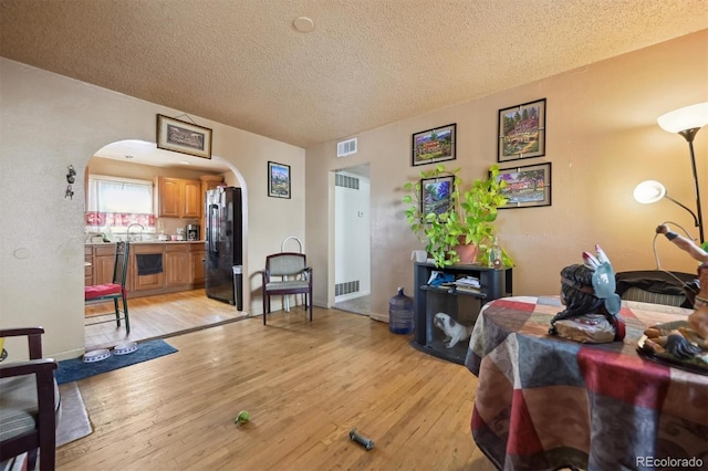 living room with a textured ceiling, light hardwood / wood-style flooring, and sink