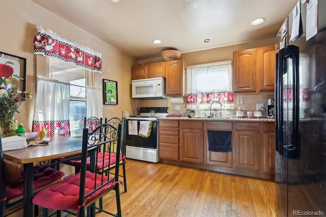 kitchen featuring light stone countertops, sink, white appliances, and light hardwood / wood-style flooring