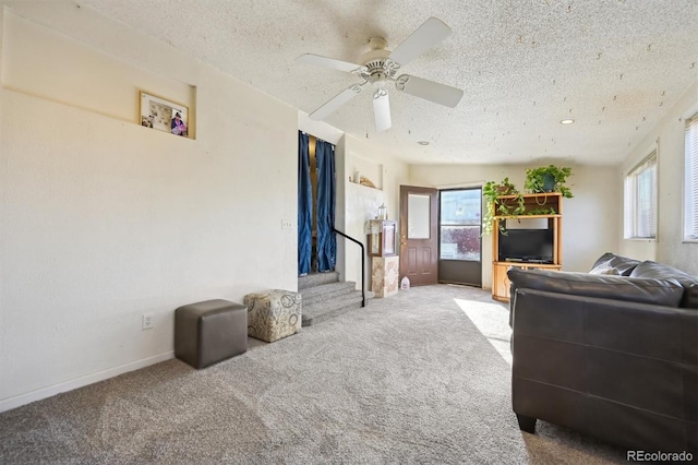 carpeted living room with a textured ceiling, ceiling fan, and a healthy amount of sunlight