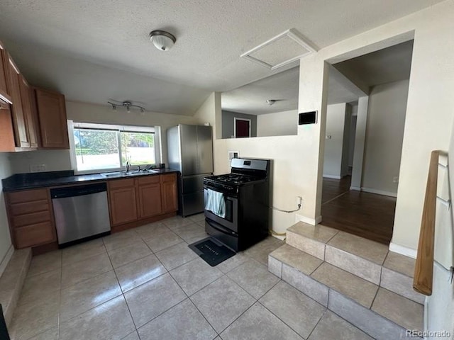 3656 W 77th Ave, Westminster, CO 80030 - kitchen featuring appliances with stainless steel finishes, lofted ceiling, dark countertops, a textured ceiling, and light tile patterned floors
