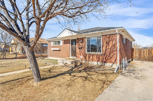 view of front facade with fence, a front lawn, and brick siding