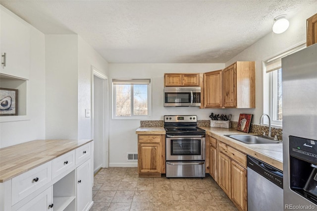 kitchen with light countertops, visible vents, appliances with stainless steel finishes, a sink, and a textured ceiling