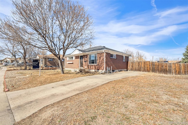 ranch-style house with concrete driveway, brick siding, and fence