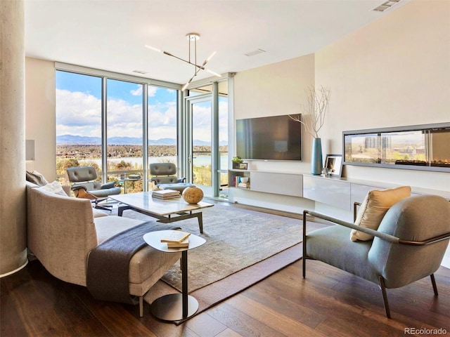 living room with hardwood / wood-style flooring, an inviting chandelier, and a wall of windows