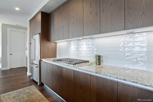 kitchen featuring decorative backsplash, dark hardwood / wood-style floors, light stone counters, and appliances with stainless steel finishes