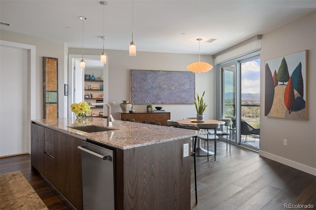 kitchen with dishwasher, sink, light stone counters, an island with sink, and pendant lighting