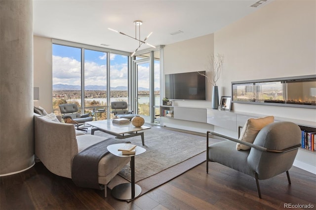 living room featuring hardwood / wood-style floors, an inviting chandelier, and a wall of windows