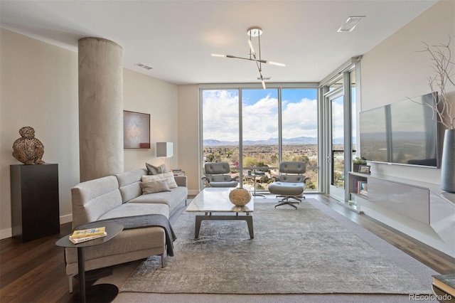 living room with a notable chandelier, a mountain view, dark hardwood / wood-style floors, and a wall of windows