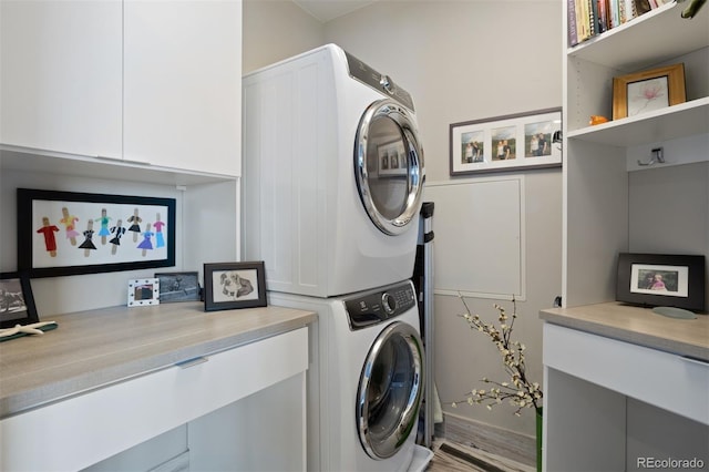 laundry area with cabinets, wood-type flooring, and stacked washer and clothes dryer