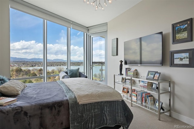 bedroom featuring carpet flooring, an inviting chandelier, floor to ceiling windows, and a water and mountain view