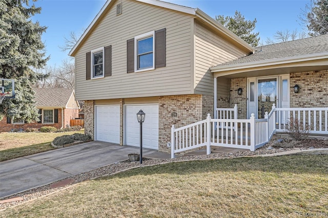 split level home with brick siding, a porch, concrete driveway, a front yard, and an attached garage