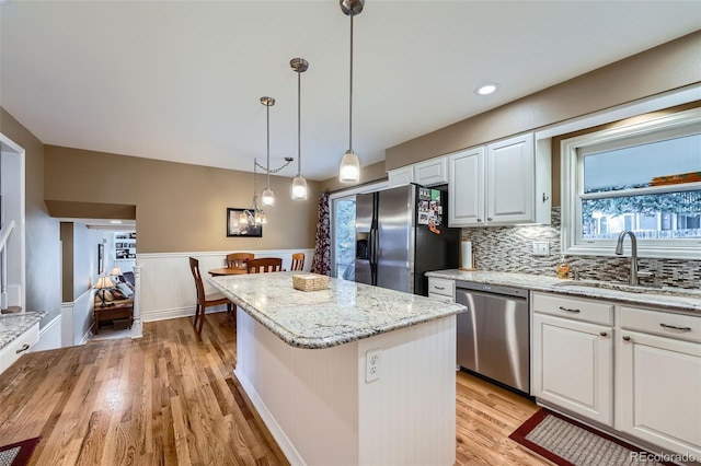 kitchen with a kitchen island, light wood-style flooring, a sink, dishwasher, and fridge with ice dispenser