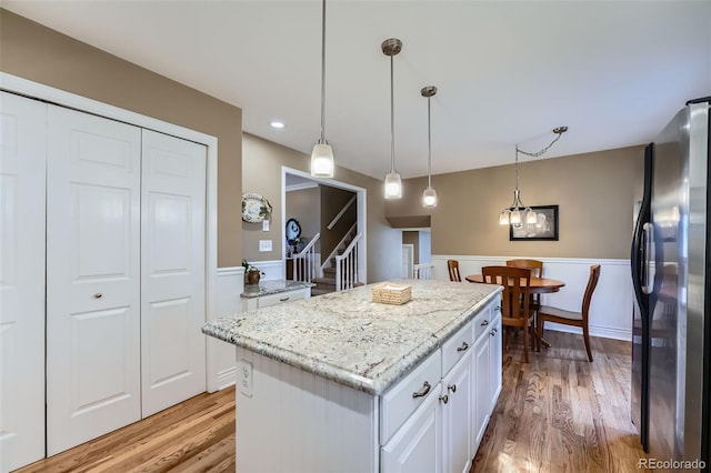 kitchen with white cabinetry, light wood-style flooring, freestanding refrigerator, and wainscoting