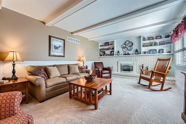 living room with visible vents, beamed ceiling, built in features, a fireplace, and light colored carpet