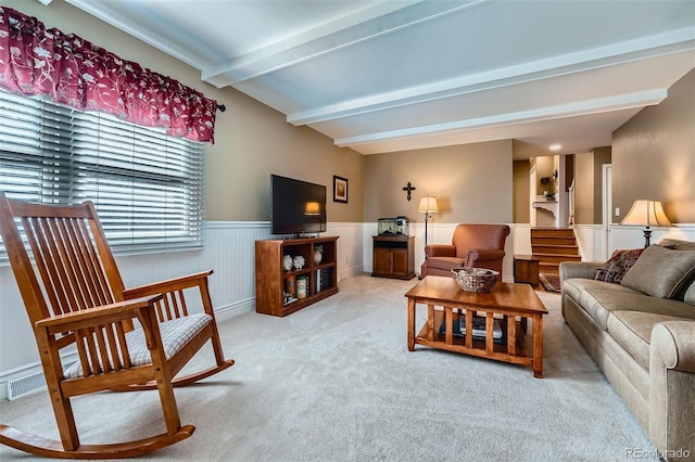 living room with lofted ceiling with beams, stairway, a wainscoted wall, and light carpet