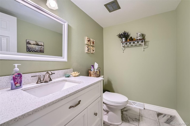 bathroom with toilet, vanity, and baseboards