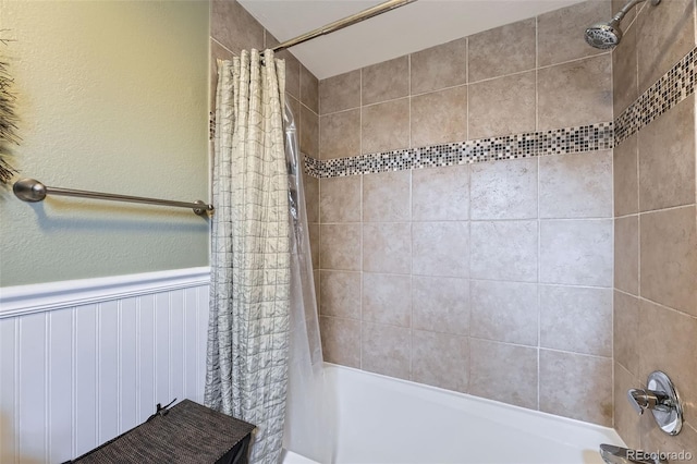 full bathroom with wainscoting and shower / bathtub combination with curtain