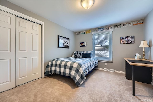 bedroom with a closet, baseboards, light colored carpet, and visible vents