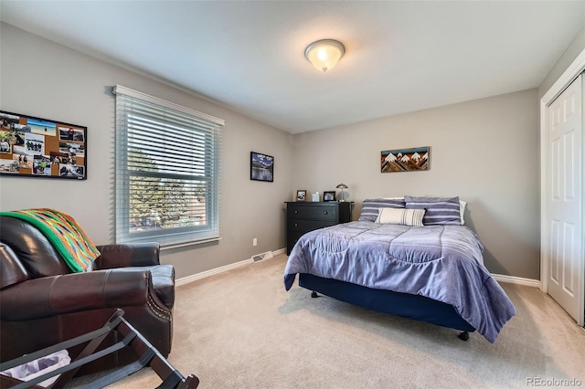 bedroom with light carpet, a closet, and baseboards