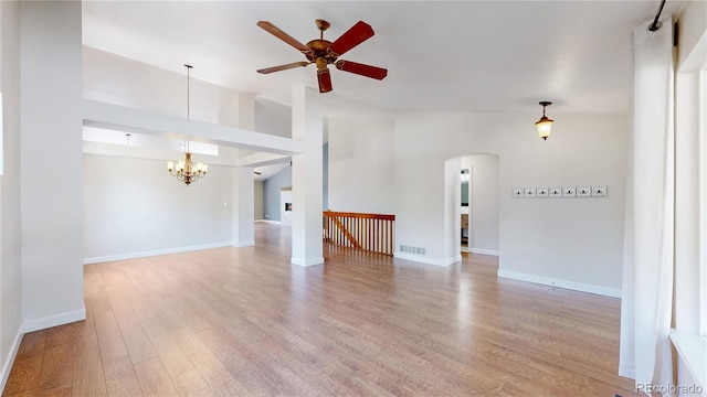 1936 E 144th Dr, Thornton, CO 80602 - unfurnished living room featuring a chandelier, arched walkways, a ceiling fan, wood finished floors, and lofted ceiling