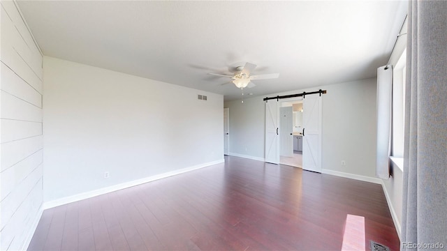1936 E 144th Dr, Thornton, CO 80602 - unfurnished bedroom with a barn door, dark wood finished floors, and a ceiling fan