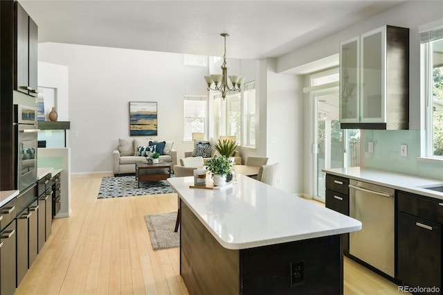 10511 Jaguar Gln, Lone Tree, CO 80124 - kitchen with appliances with stainless steel finishes, light countertops, light wood-style floors, a chandelier, and a kitchen island