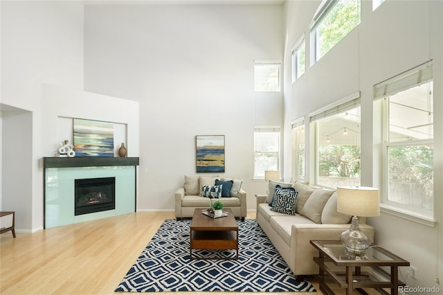 10511 Jaguar Gln, Lone Tree, CO 80124 - living area featuring a towering ceiling, wood finished floors, a glass covered fireplace, and baseboards