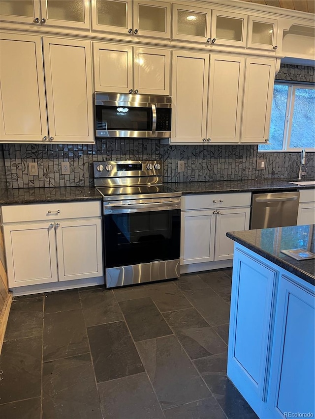 kitchen featuring sink, dark stone countertops, dark tile patterned floors, white cabinetry, and stainless steel appliances