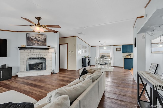 living room with wood finished floors, ceiling fan, ornamental molding, vaulted ceiling, and a glass covered fireplace