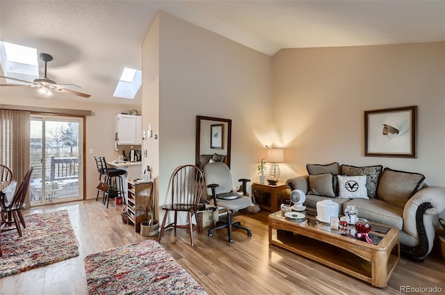 living room featuring hardwood / wood-style floors, ceiling fan, and vaulted ceiling with skylight