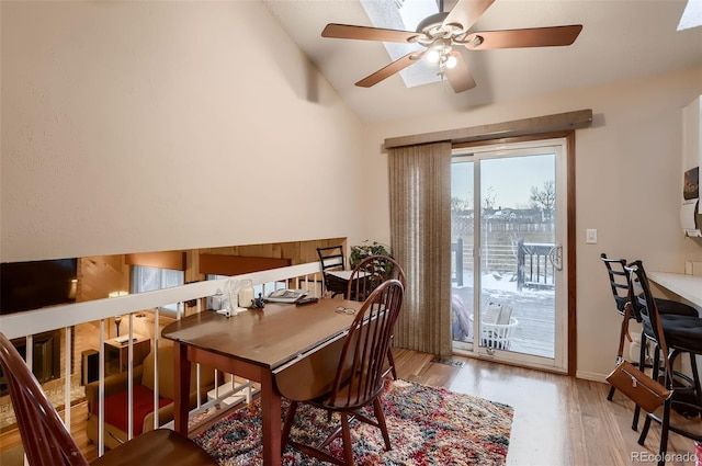 dining space with ceiling fan, light hardwood / wood-style floors, and vaulted ceiling