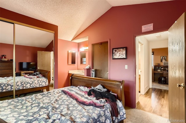 carpeted bedroom featuring a textured ceiling, a closet, and lofted ceiling