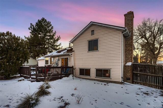 snow covered rear of property with a deck