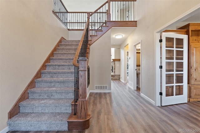 staircase with a high ceiling and hardwood / wood-style floors