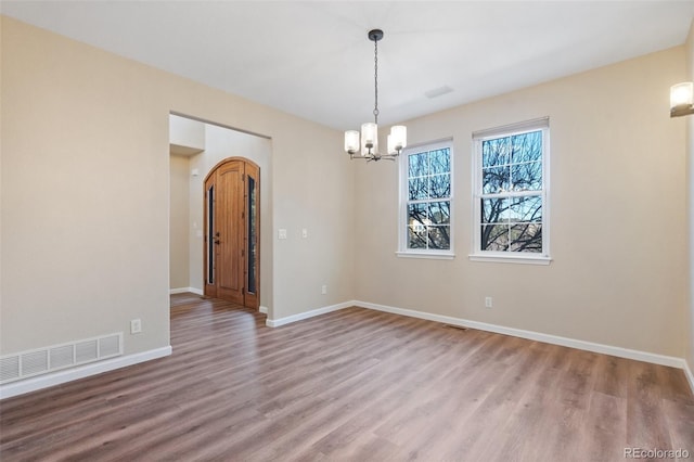 empty room featuring light hardwood / wood-style flooring and a chandelier