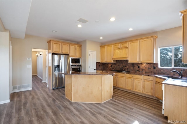 kitchen featuring appliances with stainless steel finishes, a center island, premium range hood, hardwood / wood-style flooring, and sink