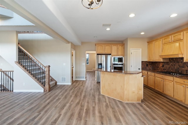 kitchen with built in microwave, custom range hood, wood-type flooring, a kitchen island, and black gas stovetop