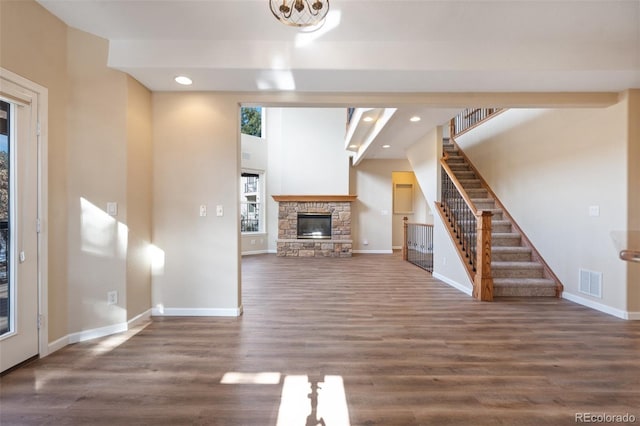 unfurnished living room featuring dark hardwood / wood-style flooring and a stone fireplace