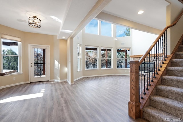 entryway with an inviting chandelier, a wealth of natural light, and hardwood / wood-style flooring