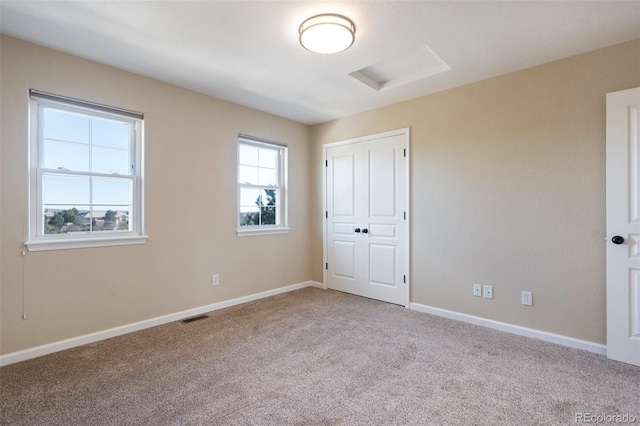 unfurnished bedroom with light colored carpet and a closet