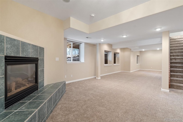 basement featuring a tile fireplace and dark carpet