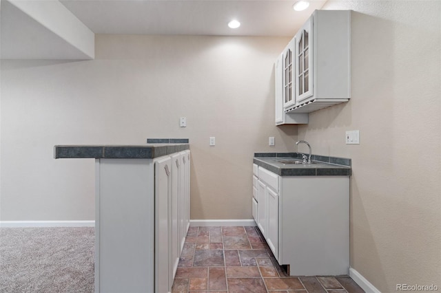 kitchen with white cabinets, sink, and dark carpet