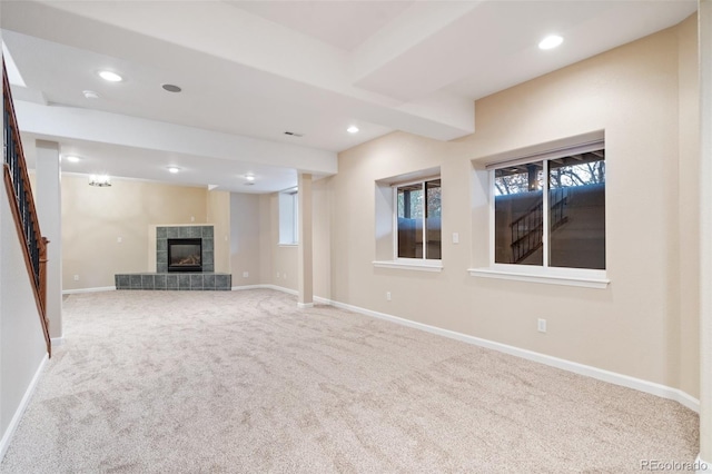 unfurnished living room featuring beamed ceiling, a fireplace, and carpet flooring